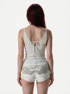 White cami with embroidered angel wings and studded white denim shorts
