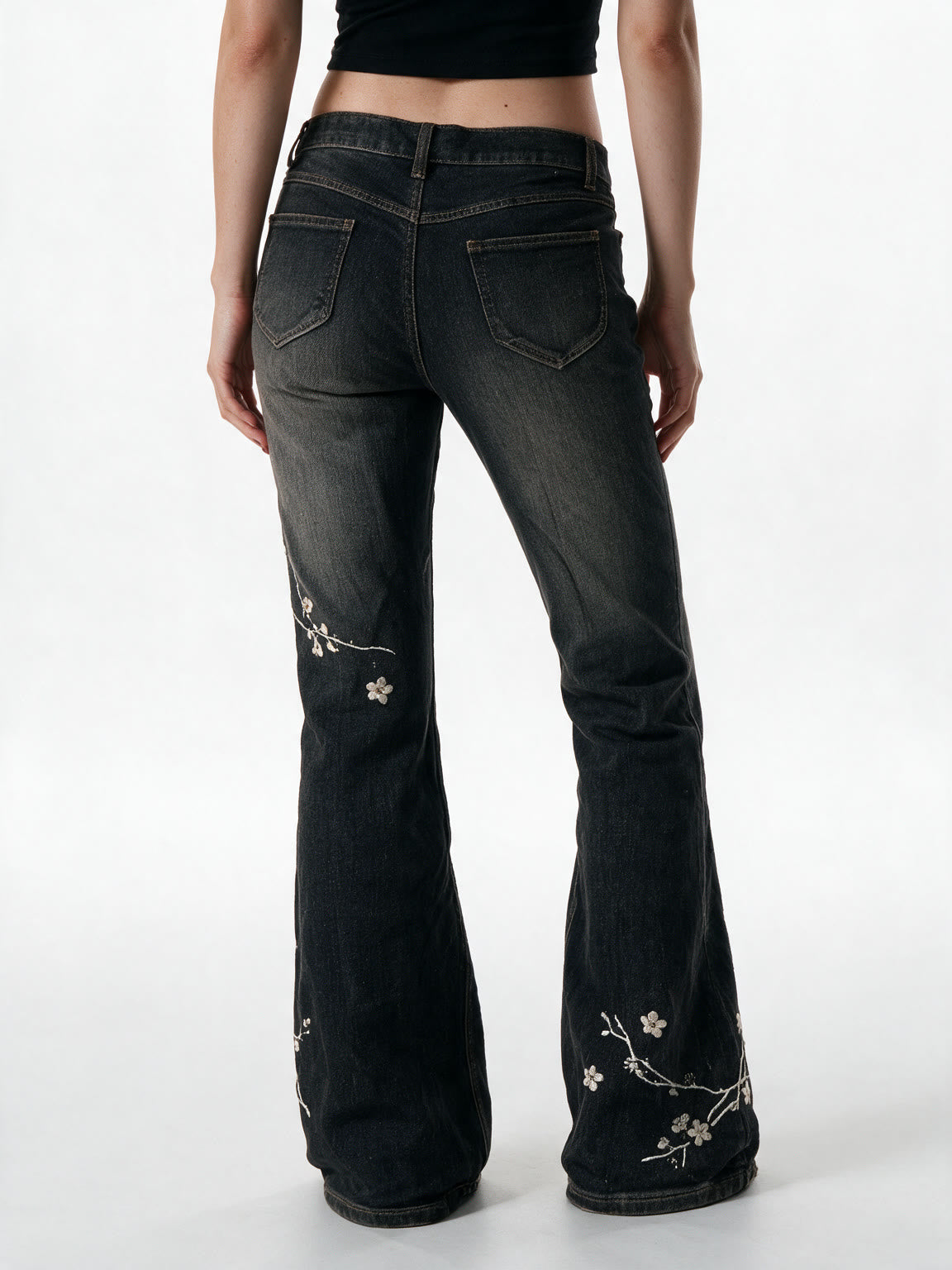 Washed black flare jeans with pale floral embroidery