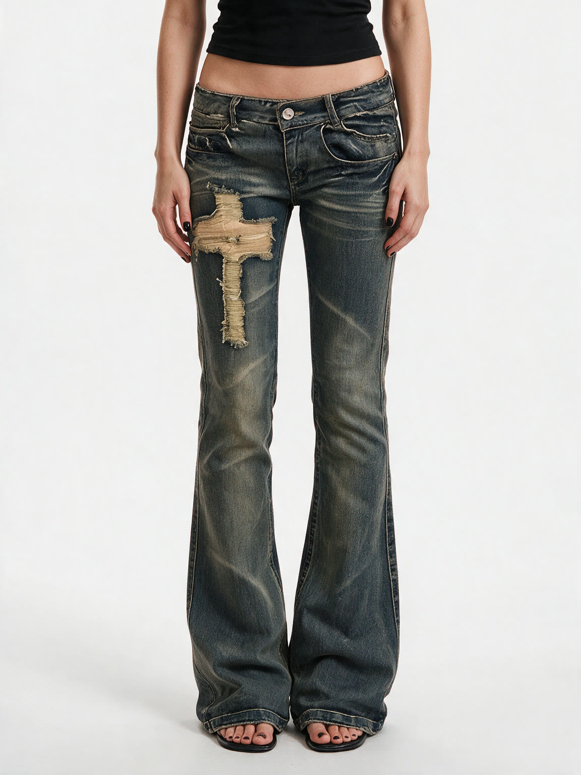 Washed blue flare jeans with a cross patch on the leg