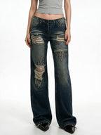 Distressed dark blue jeans with rivet patches