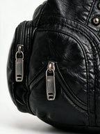 Black studded hobo bag with braided handles and tassel zips