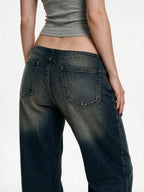 Distressed dark blue jeans with rivet patches